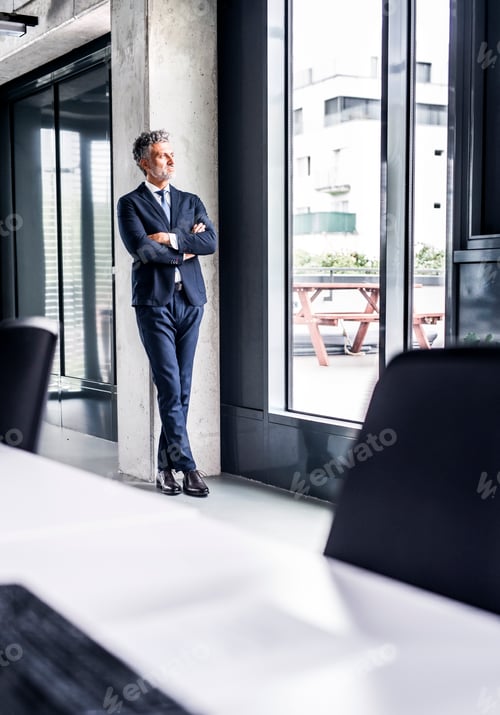Preview: Mature businessman standing in office loooking out of window