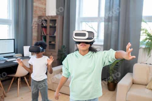 Preview: Two kids in vr headsets and casualwear watching online video on virtual display