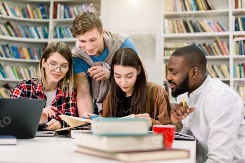 Preview: Portrait of four positive multiracial friends students, sitting at the table and preparing for exams