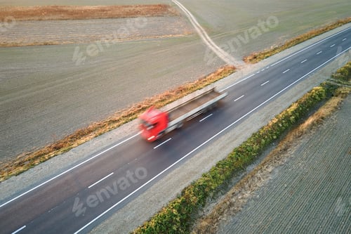 Preview: Aerial view of blurred fast moving semi-truck with cargo trailer driving on highway hauling goods in