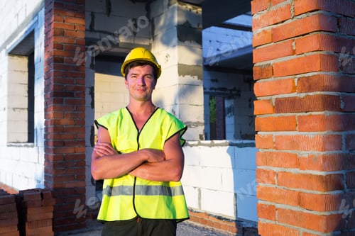 Preview: Project architect stands near construction site of a house with the walls