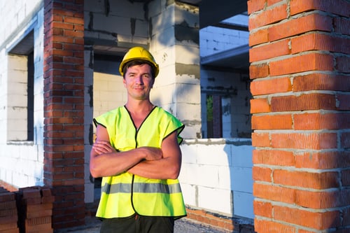 Construction Worker Poses at Unfinished Building Site