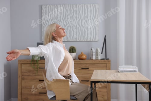 Preview: Mature woman stretching at table in office