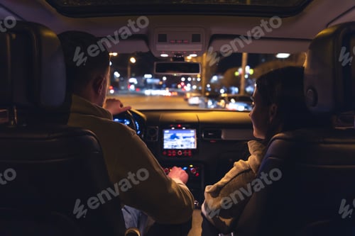 Preview: Man and woman in a car at night, view from the car.