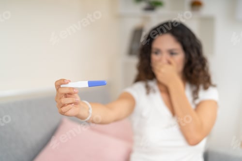 Preview: Surprised woman looking at a pregnancy test