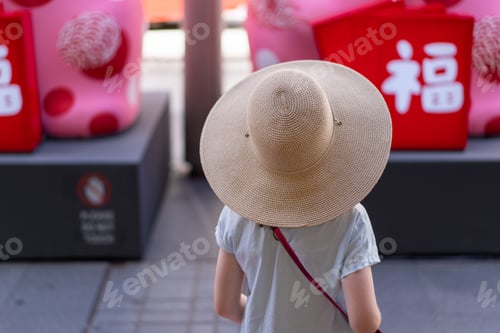 Preview: young girl child from behind with a hat on outdoors in the city exploring