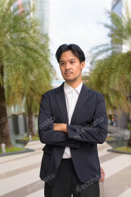 Preview: Portrait of Asian businessman outdoors in the city thinking