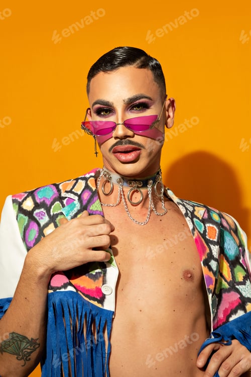 Preview: Portrait of young drag queen laughing in a colorful dress on a yellow background