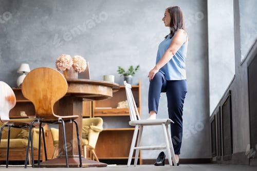 Preview: Female office worker stand in yoga pose twisting spine using chair.
