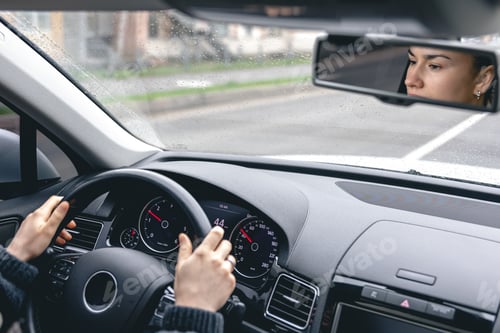 Preview: Woman drive a car reflects in back view mirror.