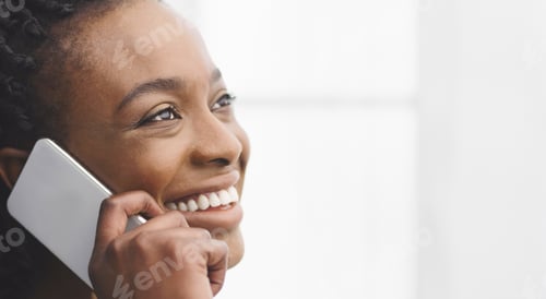 Preview: Happy young African American woman chatting on the phone, closeup