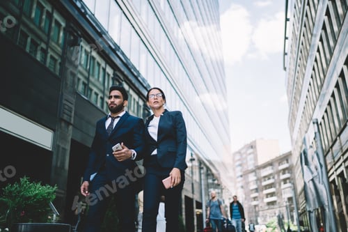 Preview: Smart business partners walking hand in hand to meeting in downtown with smartphone on way