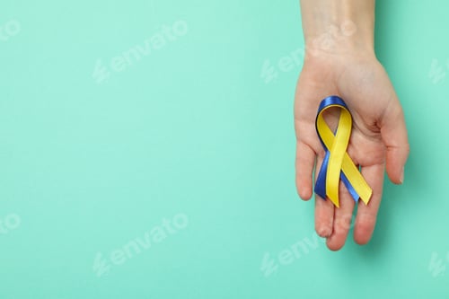 Preview: Female hands hold Down's syndrome awareness ribbons on mint background