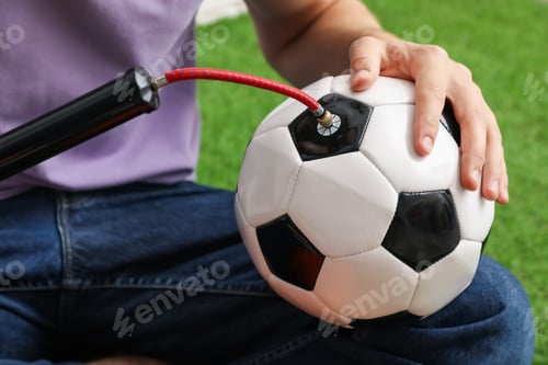Preview: Man inflating soccer ball with manual air pump indoors, closeup
