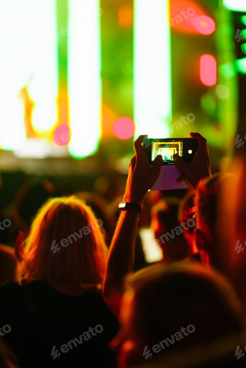 Preview: Hand with a phone records live music festival. People taking photographs with smart phone.