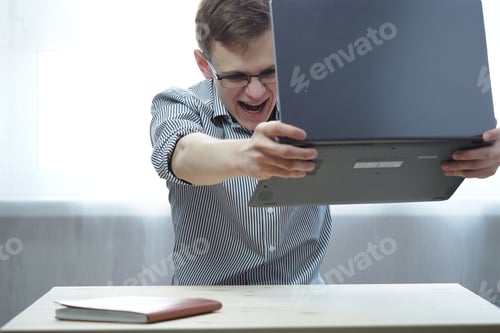 Preview: A young man is angry with a computer in his hands. Fatigue and emotions from distance education or w