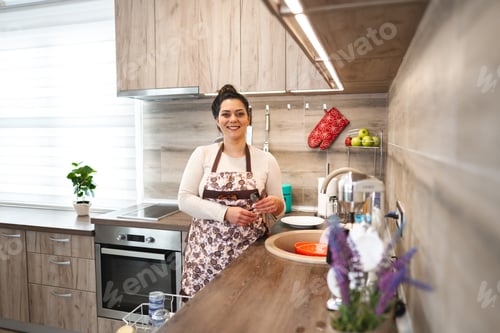 Preview: Happy woman wearing apron in the kitchen