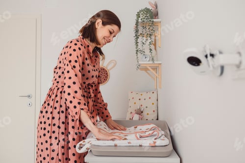 Preview: Young pregnant adult woman doing everyday things at home. Preparing room and a bed for her new comin