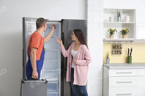 Preview: Male technician talking with client near refrigerator in kitchen