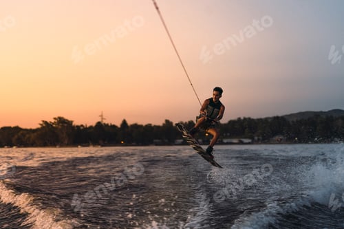 Vorschau: Latino-Mas beim Wakeboarden in einem See mit Bergen im Hintergrund