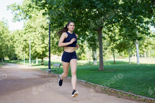 Preview: A young woman is jogging in a park, engaging in outdoor fitness and cardio