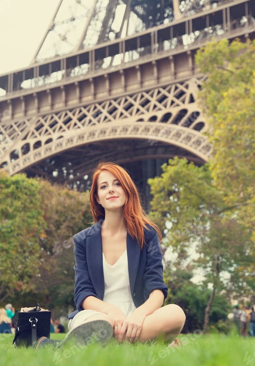Preview: Redhead girl sitting near Eiffel tower.