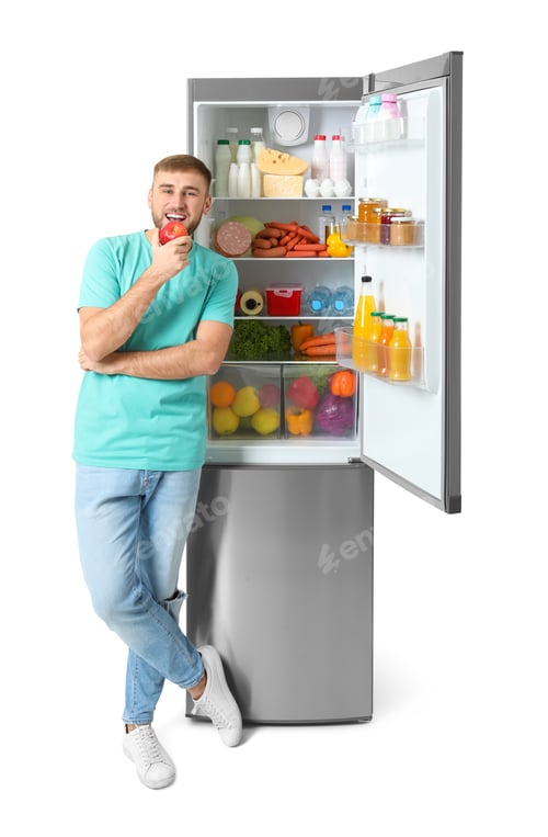 Preview: Young man eating apple near open refrigerator on white background