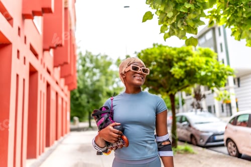 Preview: Close-up of a modern african woman holding inline skates outdoors
