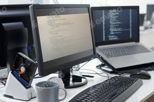 Preview: Computer monitor with decoded data on screen and laptop of programmer