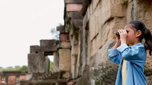 Preview: An Asian woman explores Phnom Wan Stone Temple using binoculars to admire its stunning architecture.