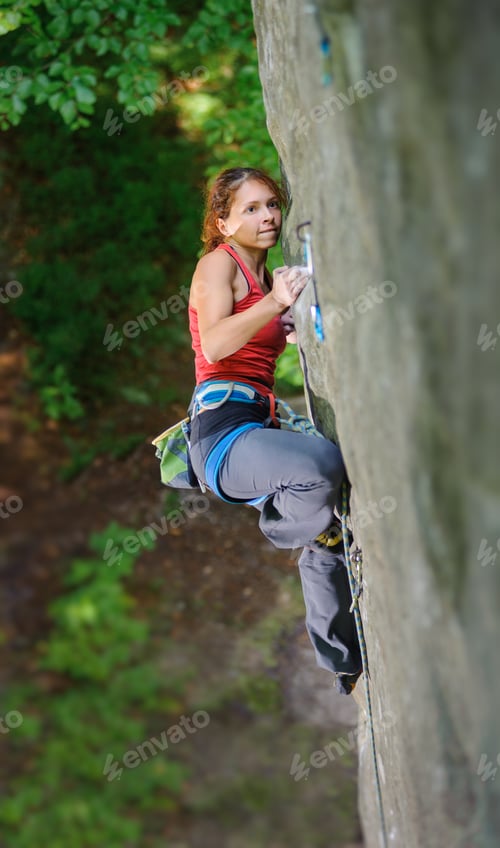 Preview: Beautiful woman climber climbing steep rock with rope