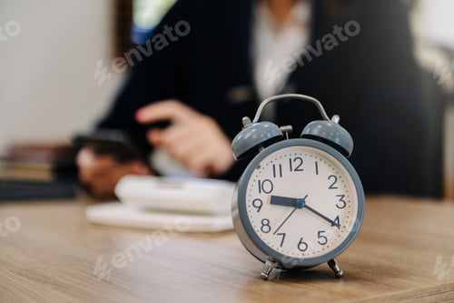 Preview: Alarm clock on the desk. Business working in modern office building or home at night using laptop.