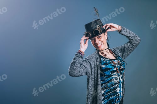 Preview: Middle-aged woman with alternative style holds her hat while looking at camera