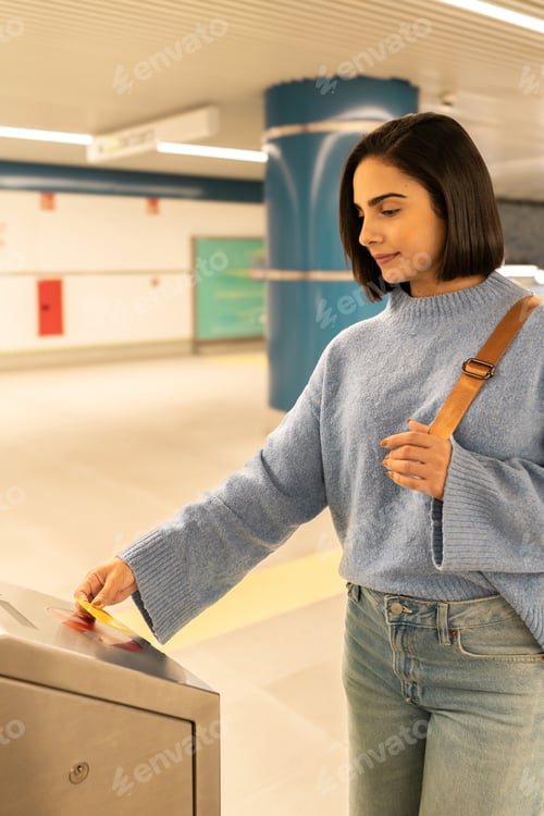 Preview: Young woman using public transport card at subway entrance