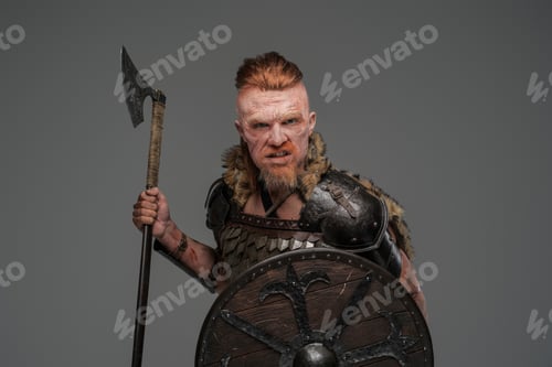 Preview: Mad redhead viking with shield and axe isolated on gray