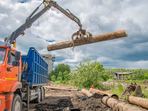 Preview: Special loader with help of grab grabbed old cast-iron pipe and loads it into truck.