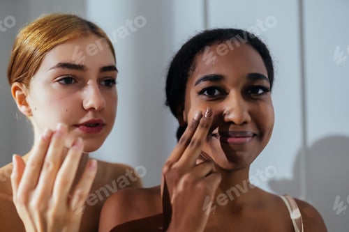 Preview: Close-up of two young women applying cream to their face