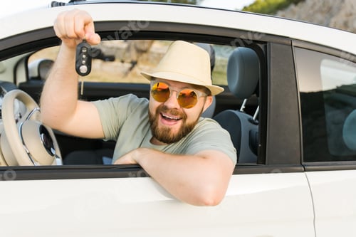 Preview: Handsome happy man showing key of new car - Rental and buy new car concept