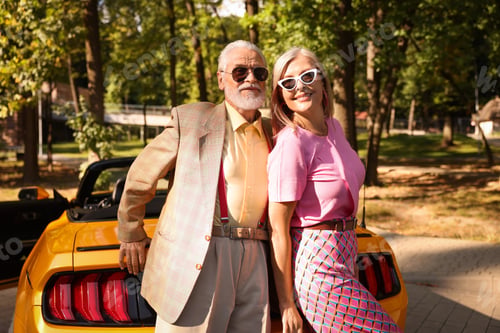 Preview: Stylish senior couple in sunglasses near modern cabriolet outdoors