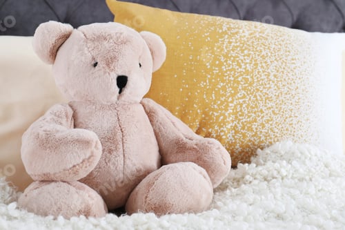 Preview: Cute teddy bear sitting on bed indoors. Space for text