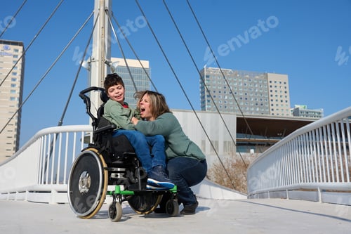 Preview: Happy boy with disability with mother having fun on a bridge in the city