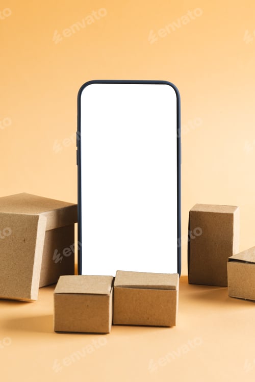 Preview: Vertical image of smartphone with blank screen and cardboard boxes, copy space on yellow background