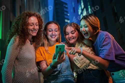 Preview: Group of young women having fun sharing media on the social media with a cellphone at night. Three