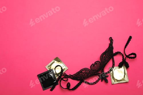 Preview: Lace mask and condoms on pink background, top view with space for text. Sex game