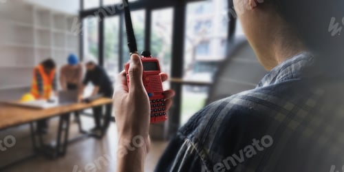 Preview: Asian male supervisor engineer standing at construction site and communicating with walkie talkie