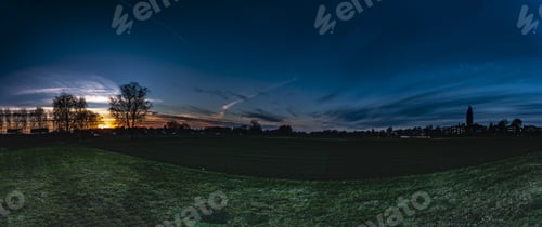Preview: Panoramic of a beautiful landscape gleaming under the sunset piercing through the cloudy sky