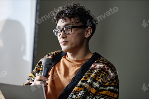 Preview: Young Adult Asian Man Holding Microphone and Presenting during Meeting