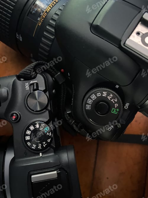 Preview: Vertical closeup shot of two professional DSLR digital cameras on a table