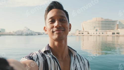 Preview: Close-up of young man standing on dock taking selfie with cell phone