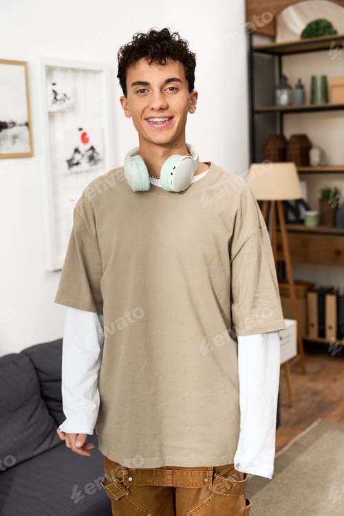 Preview: Stylish teenager enjoying leisure time at home in comfortable fashion attire with headphones